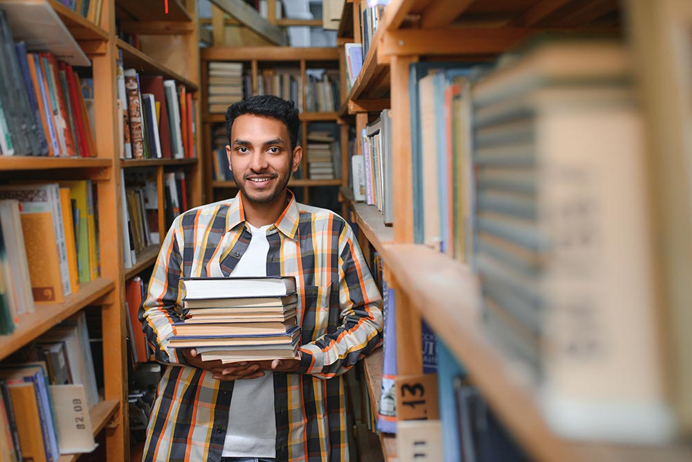 Young researcher in library considering how to write a research proposal